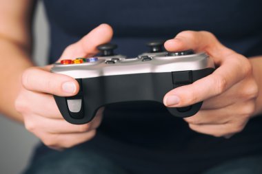 Genç kadın bir gamepad kullanarak video oyunu oynar