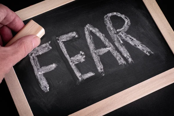 Hand erasing the word Fear on chalkboard — Stock Photo, Image
