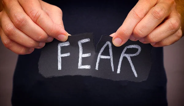 Woman ripping Fear word written on black paper — Stock Photo, Image