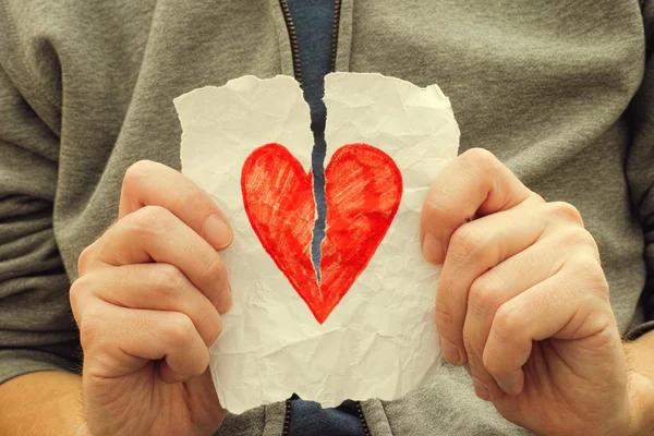 Young man ripping red heart on a piece of paper — Stock Photo, Image