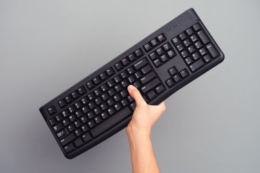 Kişi siyah kablosuz klavye onun elinde tutar.