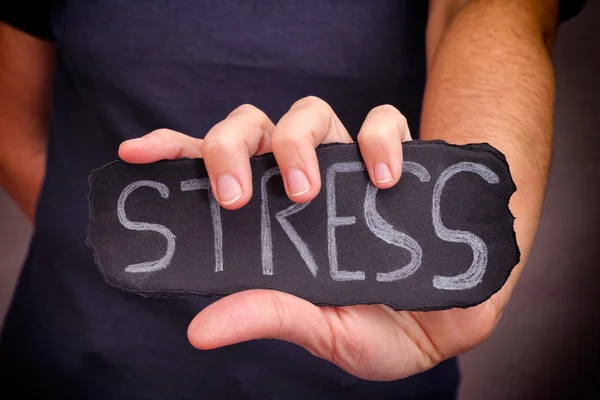 Vrouw houdt Stress woord geschreven op zwart papier — Stockfoto