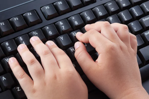 Child typing something on black computer keyboard — Stock Photo, Image