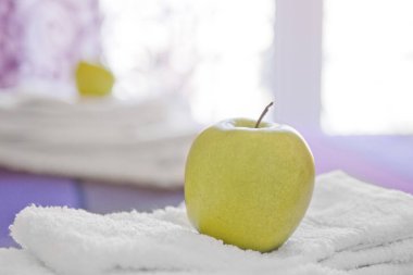 Havluların üzerindeki elmanın üzerine yakın plan. Pencereden gelen doğal ışık.