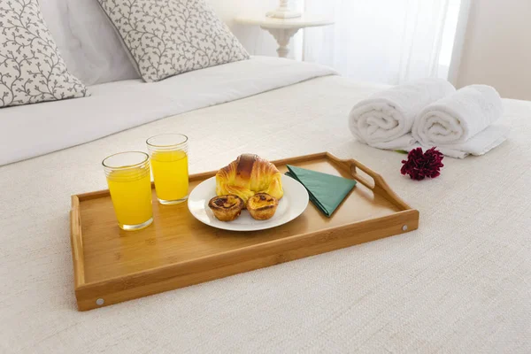 Breakfast tray in bed with delicious pastry and orange juice