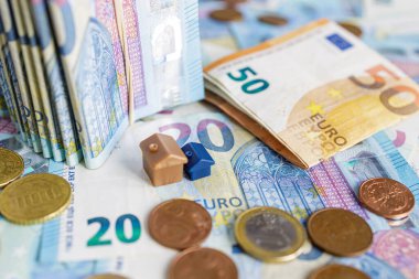 Avrupa 'nın arka planındaki ev modeli. Paralarla çevrili 20-50 avroluk banknotlar. Emlak konsepti, ev kredisi, emlak yatırımı.