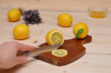 Bıçaklı el ahşap masada limon kesiyor.