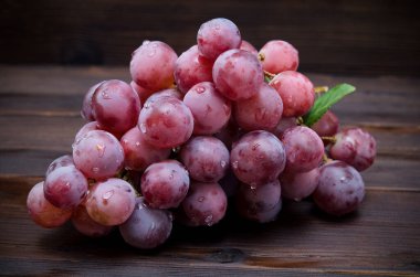 Bir demet pembe üzümlü ve siyah bir anahtarın içinde su damlaları var.