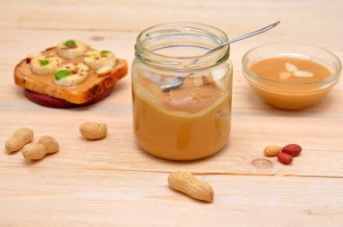 Fıstık ezmesi ve fıstık ezmesi kavanozu masaya serpilmiş.