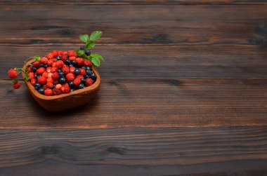 Orman meyveleri ahşap arka planda bir kasede, kopyalama alanı