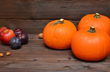 Sonbahar meyveleri kabak, erik, elma ve fındık ile ahşap arka planda ve nesne için yer