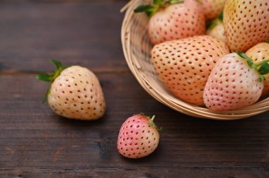 Olgun böğürtlenler sepetten dökülüp yakın planda ahşap bir masaya konur.