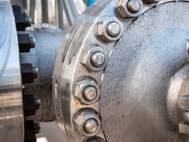 Ağır metal flanşla birleşince endüstriyel boru hattında büyük vida ve cıvatalar var.