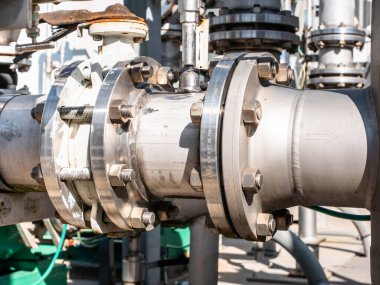 Endüstriyel bir pompa tabanında büyük bir boru üzerine vidalanmış metal montajlar ve eklemler.