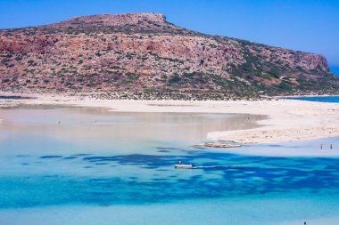 Balos Körfezi manzaralı, beton, Yunan, yazın, beyaz kum, deniz ve açık mavi gökyüzü, tropikal atmosfer bir tekne turist taşır.