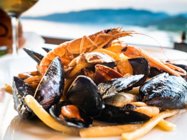 Akdeniz 'deki bir İtalyan restoranında ılık bir bahar akşamında karışık taze balıklı spagetti tabağı. Kabuklu deniz hayvanları ve midyelerle.