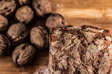 Elle pişirilmiş ekmek, arka planda fındık ve mısır gevreği, ahşap masada ev yapımı ekmek.