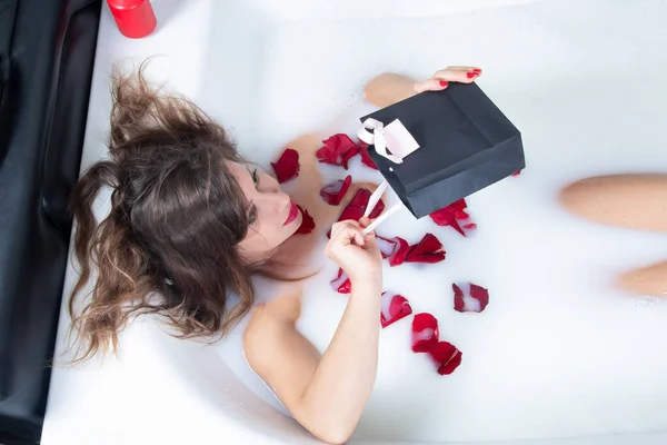 Frau Einem Milchbad Mit Roten Rosenblättern Und Öffnet Ein Paket — Stockfoto