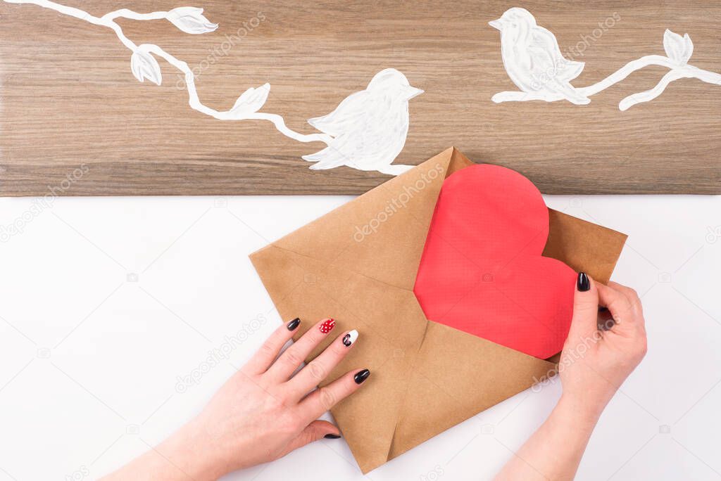 Hands cut out with scissors a paper heart. Kraft paper envelope. love letter preparation for valentines day. a letter from a lover.Making a gift from paper.DIY products,hand made.