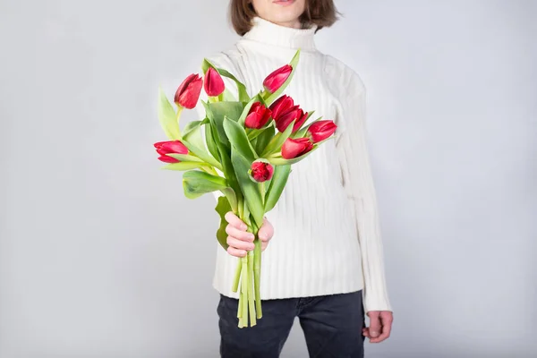 Guy holds flowers. Tulips in the hands of a young man. Flower congratulations for women.Male hands with bouquet of spring flowers close up, copy space. Hands with flowers