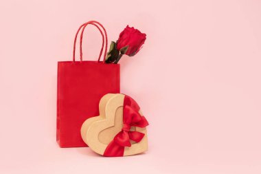 İçinde gül ve kalp şeklinde fiyonklu bir kutu olan kağıt bir hediye çantası. Sevgililer günü hediyeleri. Bir sürpriz, aşkın sembolü.