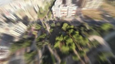 Şehir parkının bulanık insansız hava aracı görüntüsü ve dinamik yakınlaşması olan konut binaları ve çevre teması için gezegen benzeri geçişler.