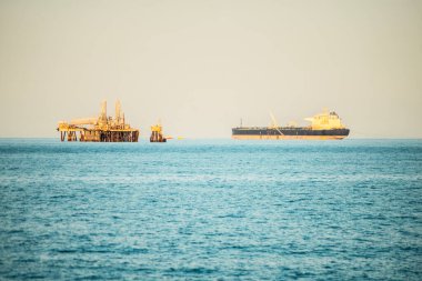 Açık denizde bir petrol platformu ve petrol tankeri. Petrol endüstrisi ve küresel petrol ve doğalgaz enerji kaynakları üretimi ve lojistiği. Artan petrol fiyatları. savaş İran