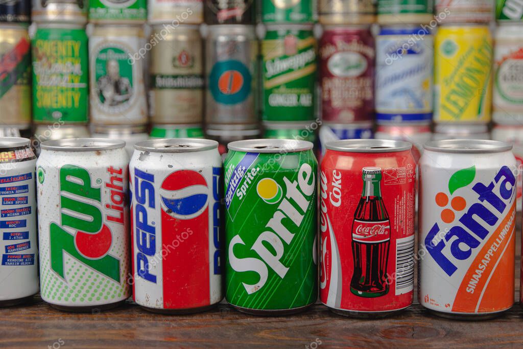 The row of most popular soft drinks on the world in vintage aluminium cans: Pepsi, Fanta, Cola, 7-up, Sprite with a background of different cans