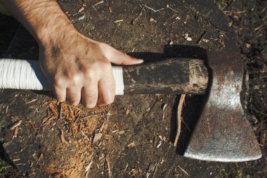 Avrupalı bir adam arka planda eski bir baltanın beyaz sapını sıkıyor.