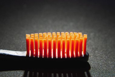 Siyah başlıklı, turuncu tüylü diş fırçası siyah arka plana yakın.