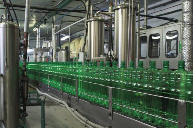Atölyede yeşil plastik şişeli otomatik taşıyıcı. Bakış açısı. Şişelenmiş içecekler üretme kavramı