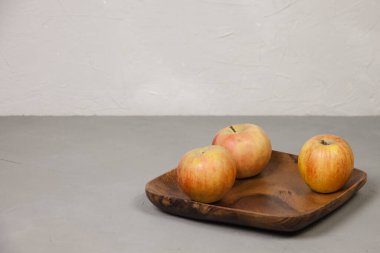 Tahta bir tabakta üç olgun elma. Olgun elma hasadı. Hasat konsepti