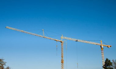 Mavi gökyüzü arka planında inşaat vinçleri