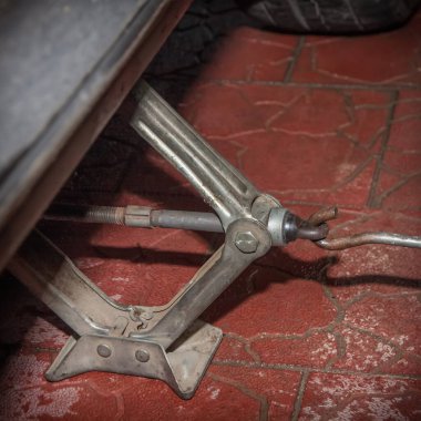 Araba, özel bir evin avlusunda, mekanik bir araba tarafından kaldırıldı. Arka planda kırmızı kiremit