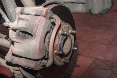 Fren diski ve kırmızı kalibreli bir araba tekerleğinin paslı ön merkezi. Tekerleksiz bir araba. Kapat.