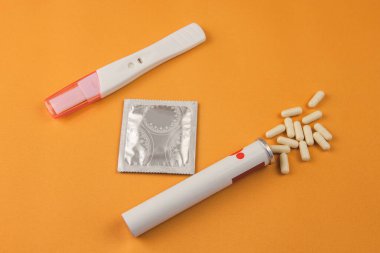 Doğum kontrol hapları, prezervatif ve sarı arka planda negatif hamilelik testi. Hamileliği önlemek için ilaç.