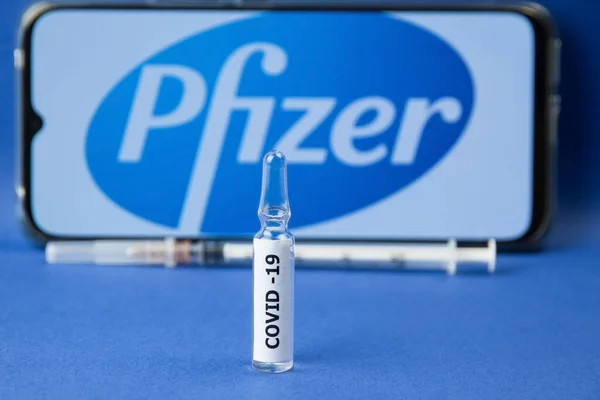Krasnodar, Rusya - 12 Ocak 2021: Pfizer logosu ve şırıngası üzerinde covid-19 etiketli ilaç ampulü. Pfizer, koronavirüsün önlenmesi için aşı üreten bir şirket.