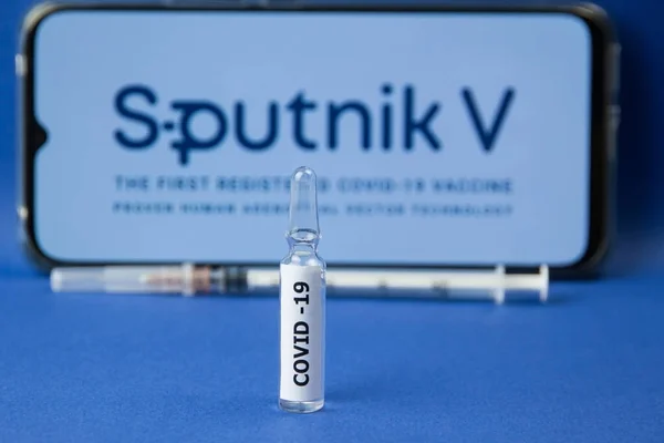 Krasnodar, Rusya - 12 Ocak 2021: Sputnik V logosu ve şırıngası üzerinde covid-19 etiketli ilaç ampulü. Sputnik V, koronavirüsün önlenmesi için aşı üreten bir şirket.