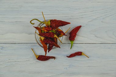 Kuru kırmızı kırmızı biber mavi ahşap arka planda cam bir kasede yatar. Yakın plan.