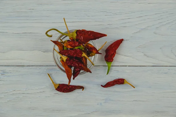 Kuru kırmızı kırmızı biber mavi ahşap arka planda cam bir kasede yatar. Yakın plan.
