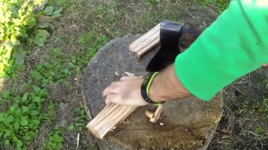 Bir adam kütüğün üzerinde odun kesiyor.