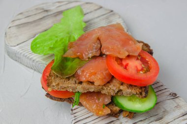 Beyaz bir köy tahtasında duran salata, sebze ve otlu kırmızı balıklı atıştırmalıklar. Sağlıklı yiyecek kavramı