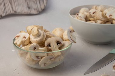 Yuvarlak kaselerde taze doğranmış şampiyonlar. Bıçak ve kesme tahtasının yanında. Yakın plan.