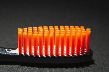 Siyah başlıklı, turuncu tüylü diş fırçası siyah arka plana yakın.