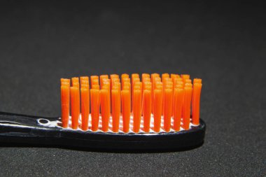 Siyah başlıklı, turuncu tüylü diş fırçası siyah arka plana yakın.