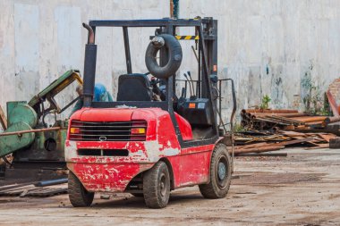Kırmızı dizel döküntü forklift kamyonu hurda metalin arka planına çarpmış. Yakın plan.