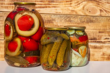 Ahşap bir arka planda cam bir kavanozda konserve sebzeler. Salatalık turşusu, domates ve kabak. Geleneksel Rus atıştırması