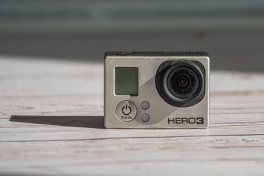 Krasnodar, Rusya - 22 Mart 2021: Eski yıpranmış ve tozlu bir kamera GoPro Kahraman 3 Black Edition, uzun gölgeli ahşap bir arka planda. Yakın plan.