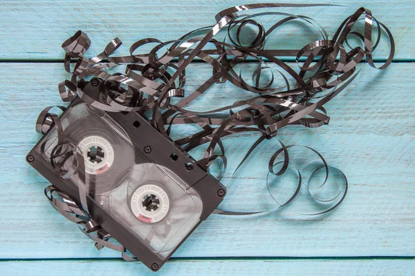 An audio tape with the film unwound lies on a blue wooden background. Top view