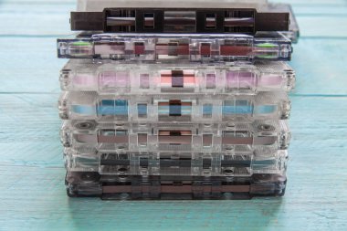 Bir yığın eski ses kaseti mavi ahşap bir arka planda duruyor. Manyetik film ve basınçlı keçeli yastıklı bir yay görülebilir. Yakın plan.